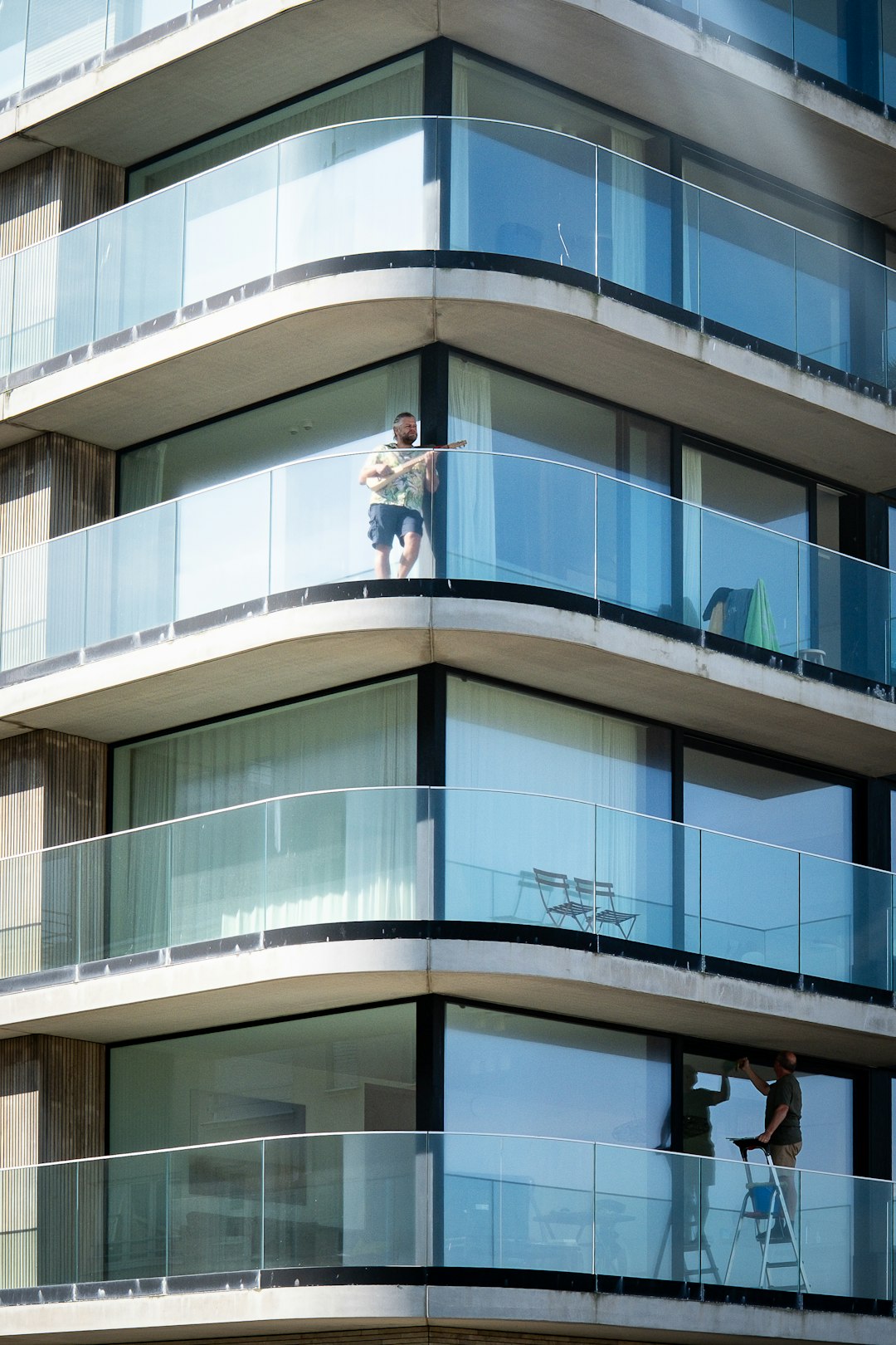man-on-balcony-of-modern-building-with-glass-railings-5y7n1uxyrb8