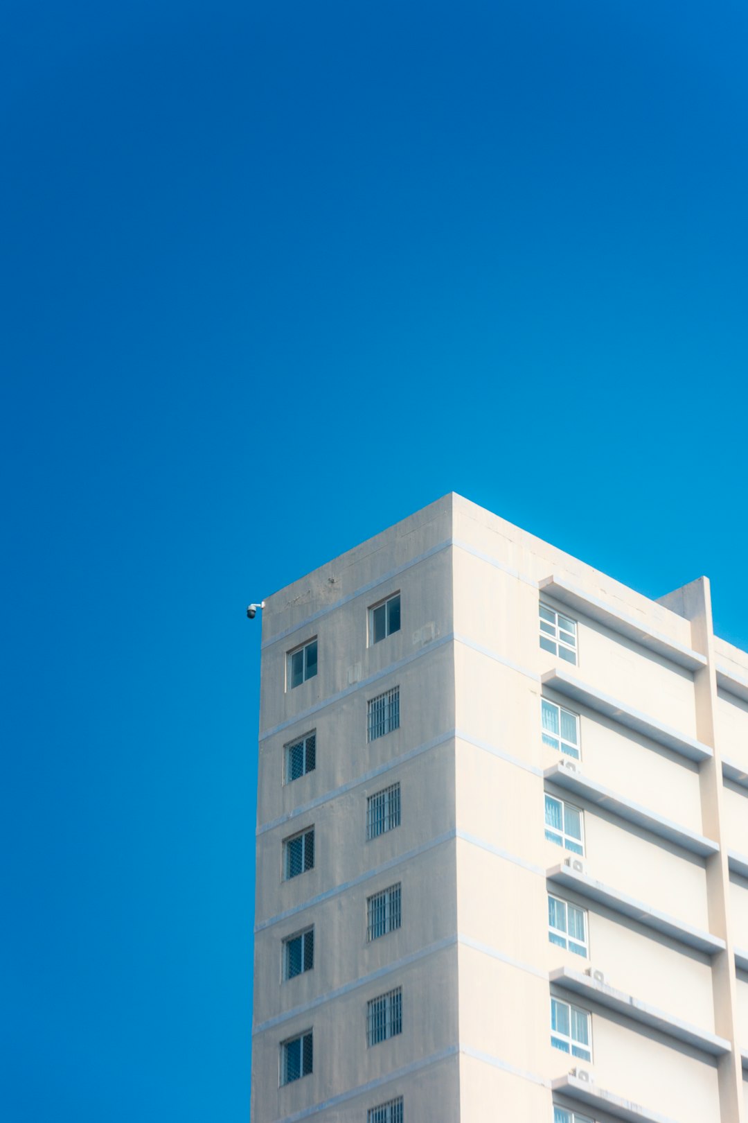 a-light-colored-apartment-building-against-a-bright-blue-sky-ye-hvizs-8y